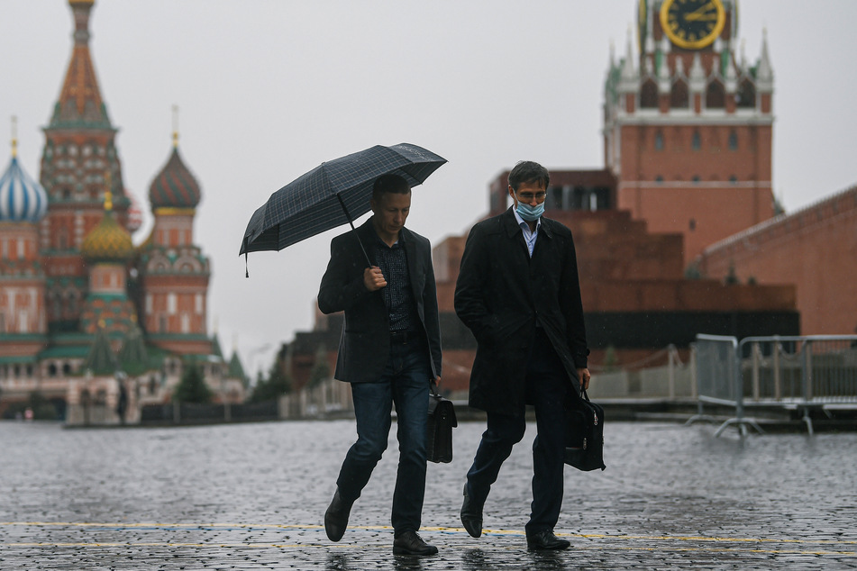 Menschen gehen bei Regen auf dem Roten Platz in Moskau.
