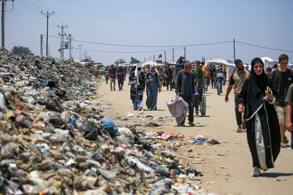 Palestinians walk on a street littered with trash in Khan Younis in the southern Gaza Strip.