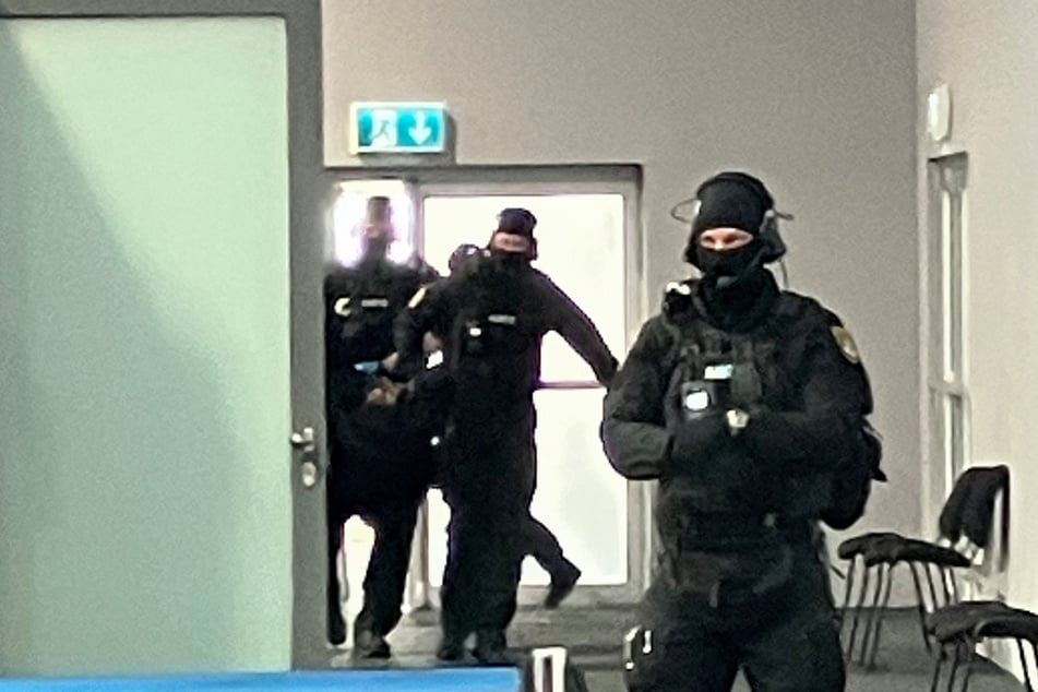 Vermummte Kräfte der Justiz tragen den Attentäter in den Gerichtssaal.