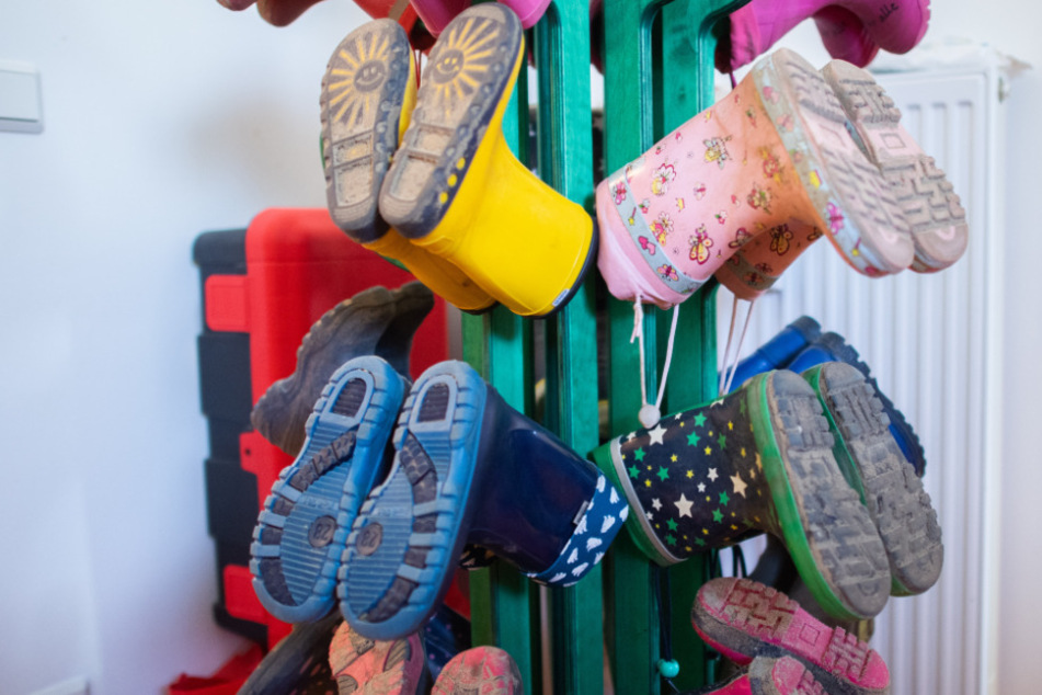 Gummistiefel von Kindern hängen in einem Kindergarten.