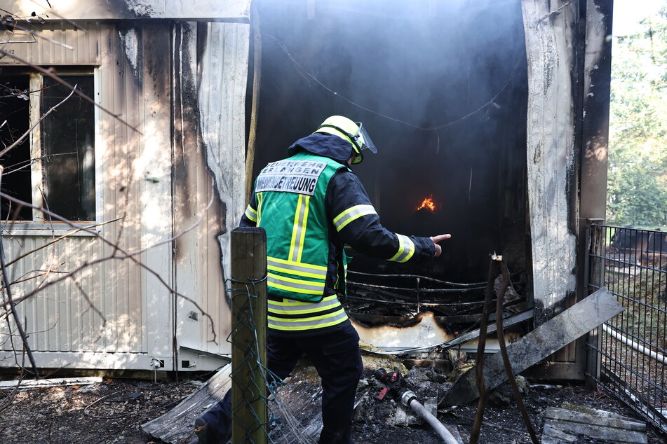 Ein Feuerwehrmann arbeitet in den qualmenden Trümmern der Erlanger Flüchtlingsunterkunft.
