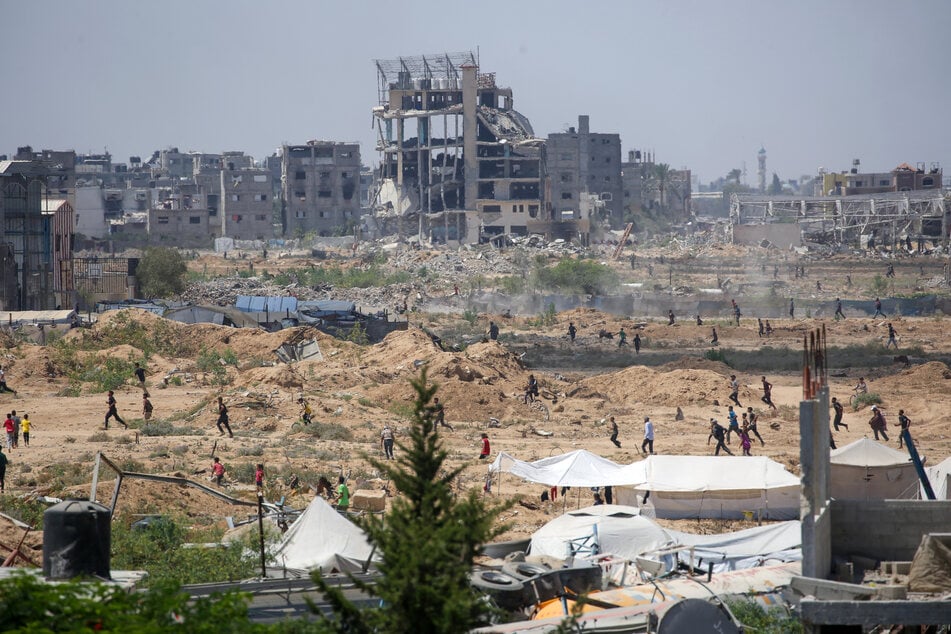 Displaced Palestinians make their way towards the site of a humanitarian aid airdrop at the Bureij camp in the central Gaza Strip on August 17, 2025.