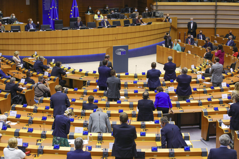 Abgeordnete des Europäischen Parlaments stehen im Parlamentssaal.