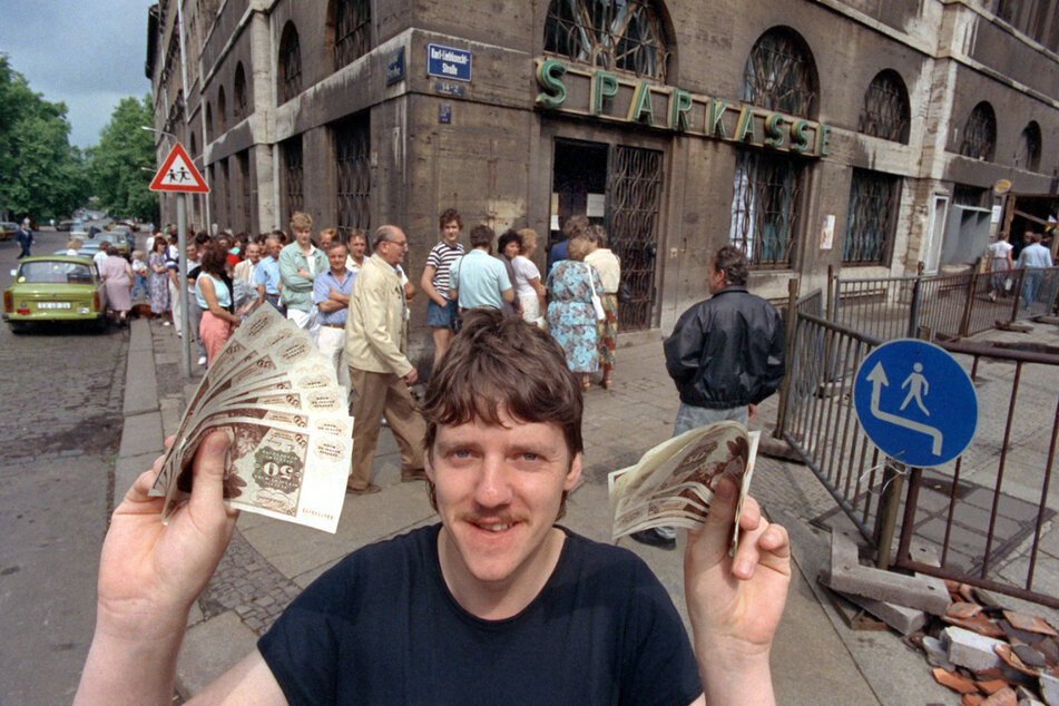 Nach langem Schlangestehen vor einer Leipziger Bank freut sich dieser junge Mann über seine D-Mark-Banknoten, aufgenommen am 1. Juli 1990, der Tag der deutsch-deutschen Währungsunion.