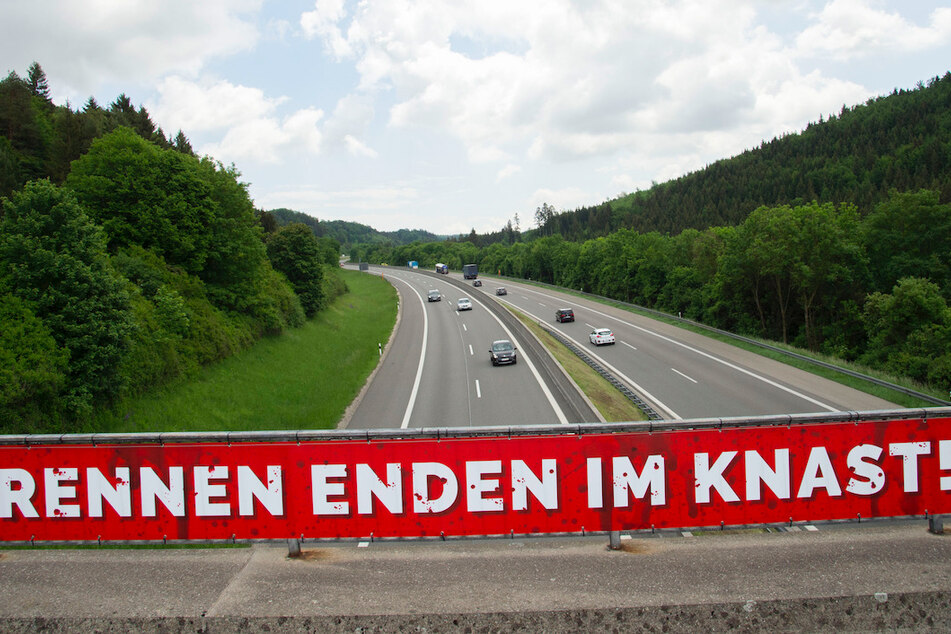 Ein Banner mit der Aufschrift "Rennen enden im Knast!" hängt an der A8.