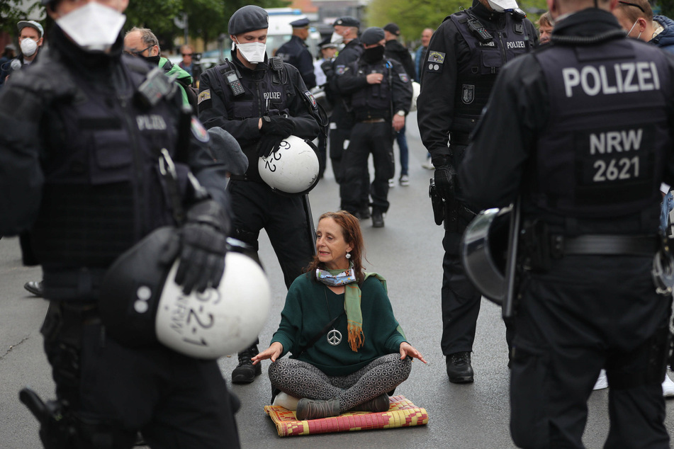 Eine Yoga-Treibende ist von Polizisten umzingelt.