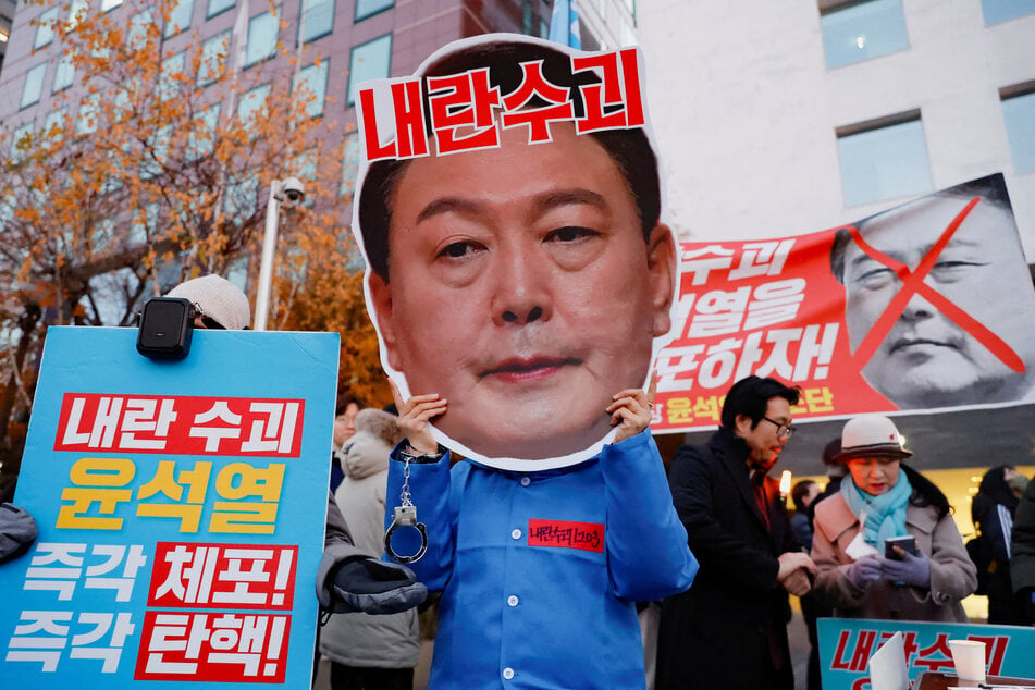 A protestor wears a cut-out of South Korean President Yoon Suk Yeol in a rally calling for his impeachment, near the National Assembly in Seoul.