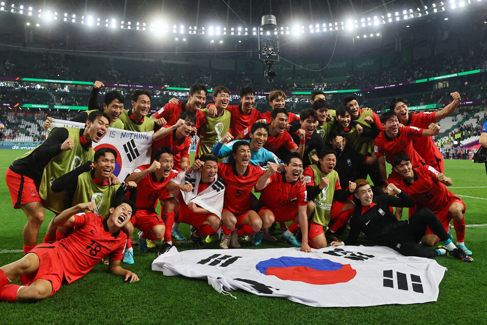 The South Korea men's national team pose with their flag after a dramatic qualification to the World Cup last 16.