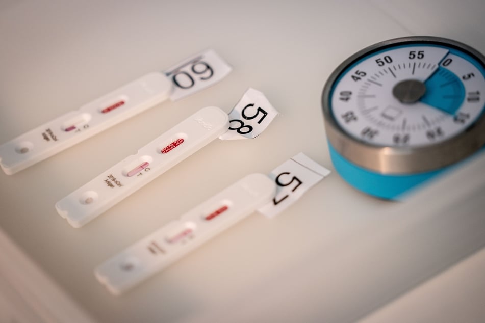 Antigen Testkasetten für den Corona-Schnelltest liegen neben Stoppuhren in Schalen.