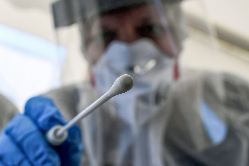Eine Mitarbeiterin vom Gesundheitsamt in Berlin hält ein Abstrichstäbchen in einer ambulanten Corona-Test-Einrichtung.