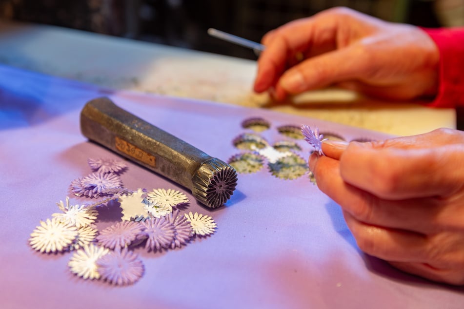 Mit Kraft und Geschick: In der Stanzerei (F.r.) werden aus Stoffbahnen kleine Blüten herausgestochen.