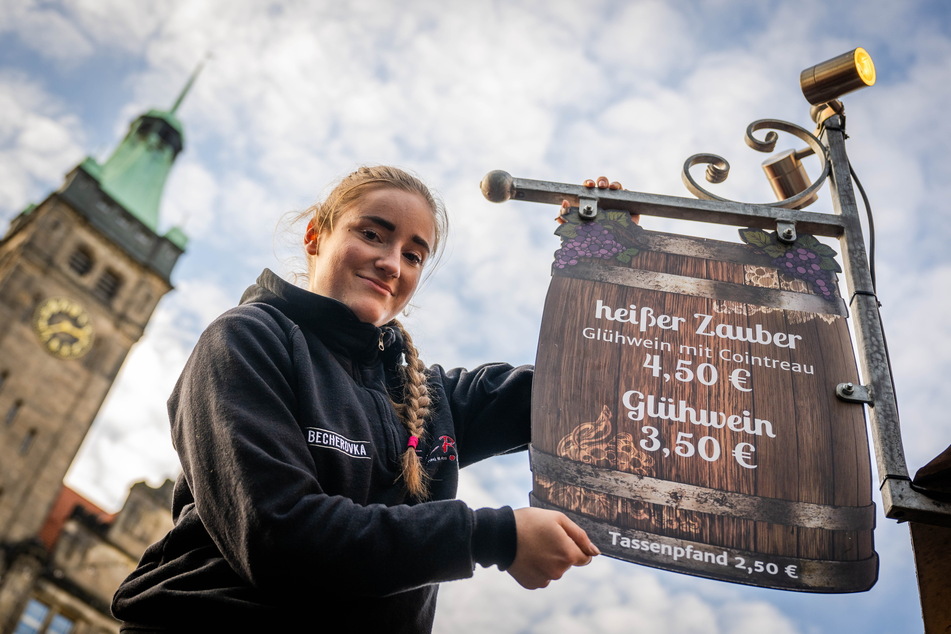 Lena Münch (18) hängt am Winzerstübchen auf dem Neumarkt ein Schild mit den Preisen für Glühwein auf.