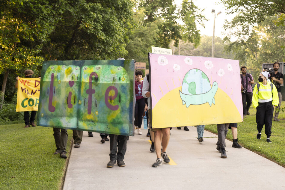 Forest defenders march with a picture of a turtle, in honor of Tortuguita, as they protest the construction of a massive police training facility outside Atlanta known as Cop City.