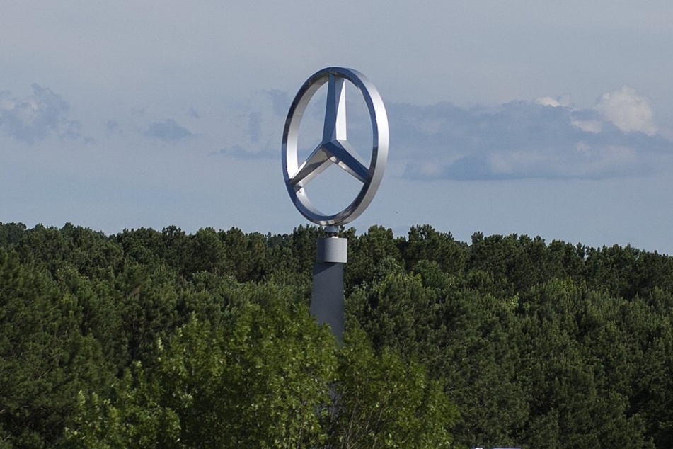A giant Mercedes-Benz logo towers over the tree line at the company's factory in Vance, Alabama.