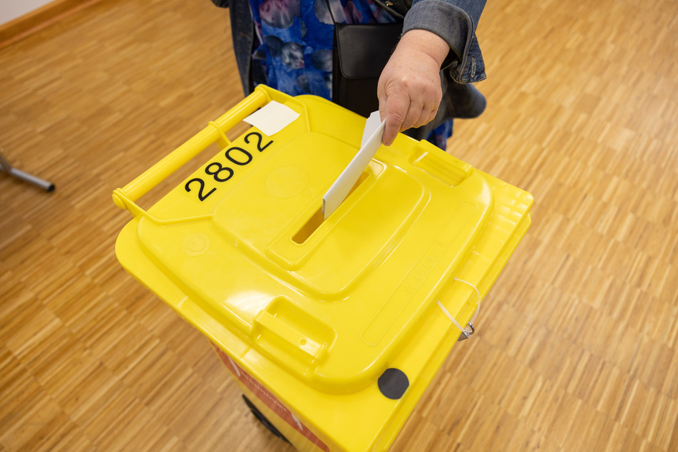 Eine Wählerin wirft ihren Stimmzettel in eine Wahlurne.