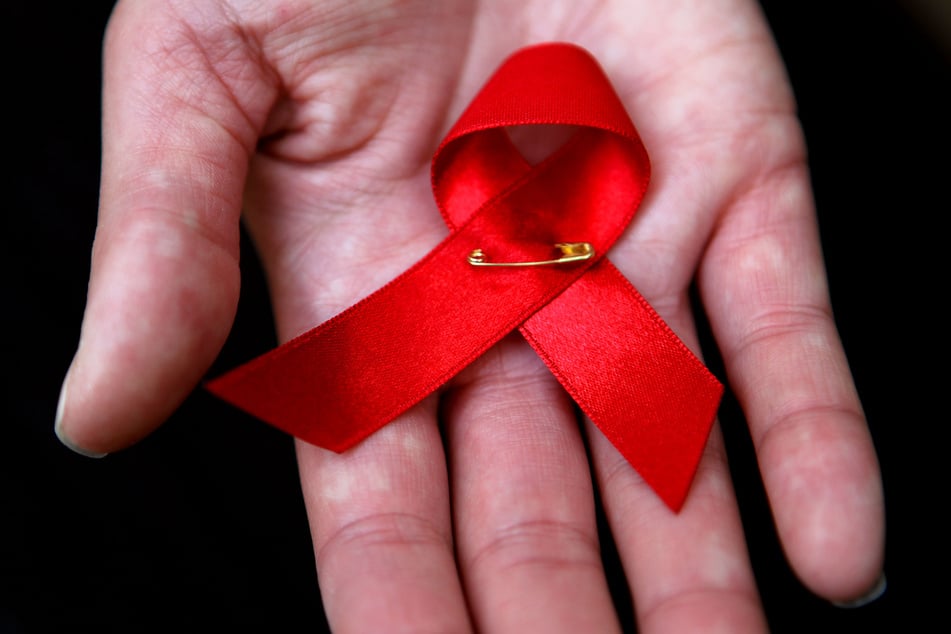 Die sogenannte Aids-Schleife gilt weltweit als Zeichen der Solidarität mit den Betroffenen.