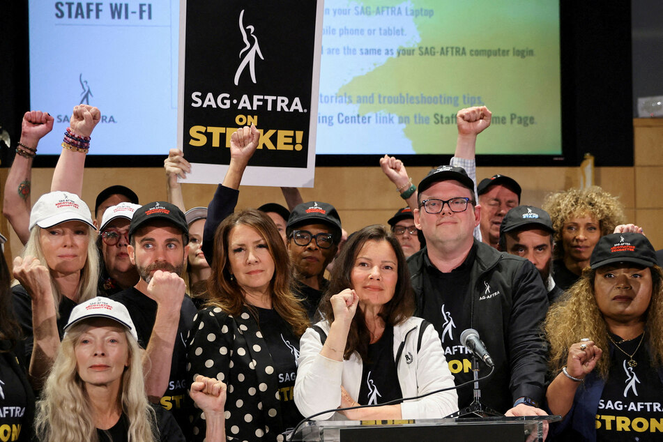 SAG-AFTRA President Fran Drescher, National Executive Director and Chief Negotiator Duncan Crabtree-Ireland, and union members raise their fists after negotiations ended with the Alliance of Motion Picture and Television Producers, triggering the actors' strike.