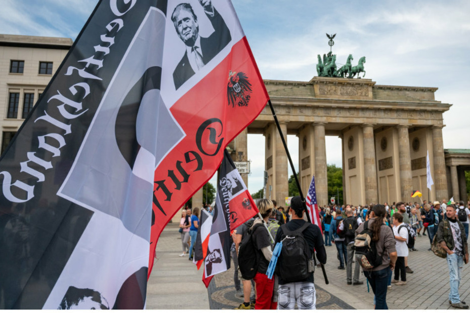 Ein Demonstrant hält vor einer Demonstration gegen die Corona-Maßnahmen eine große Reichsflagge vor dem Brandenburger Tor.