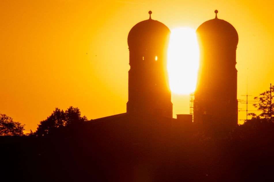 Die Sonne geht zwischen den Türmen des Münchner Liebfrauendoms auf.