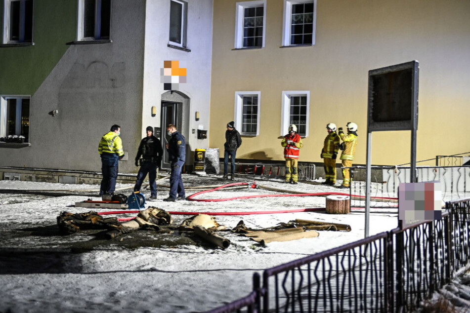 Die Einsatzkräfte vor dem Geschäft. Davor liegen verkohlte Teppiche.