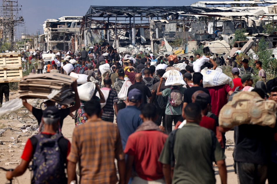 Displaced Palestinians carry bags of humanitarian aid they received at a distribution center run by the US and Israeli-backed Gaza Humanitarian Foundation in the central Gaza Strip on August 4, 2025.