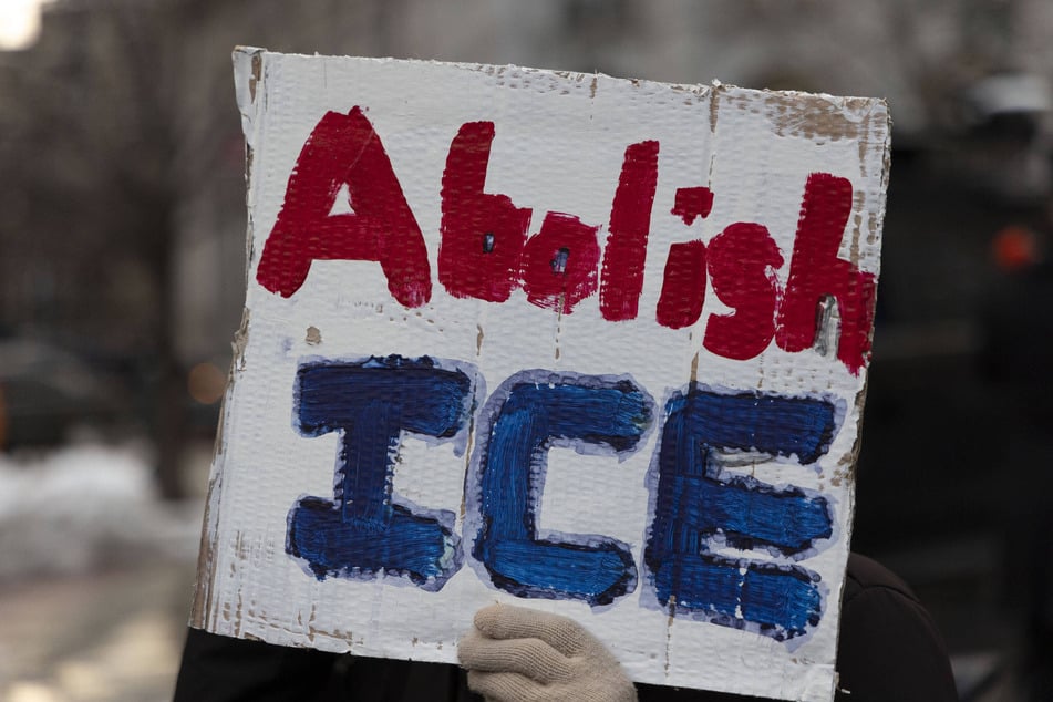 A protester holds a sign reading "Abolish ICE" in opposition to Donald Trump's mass deportation agenda.