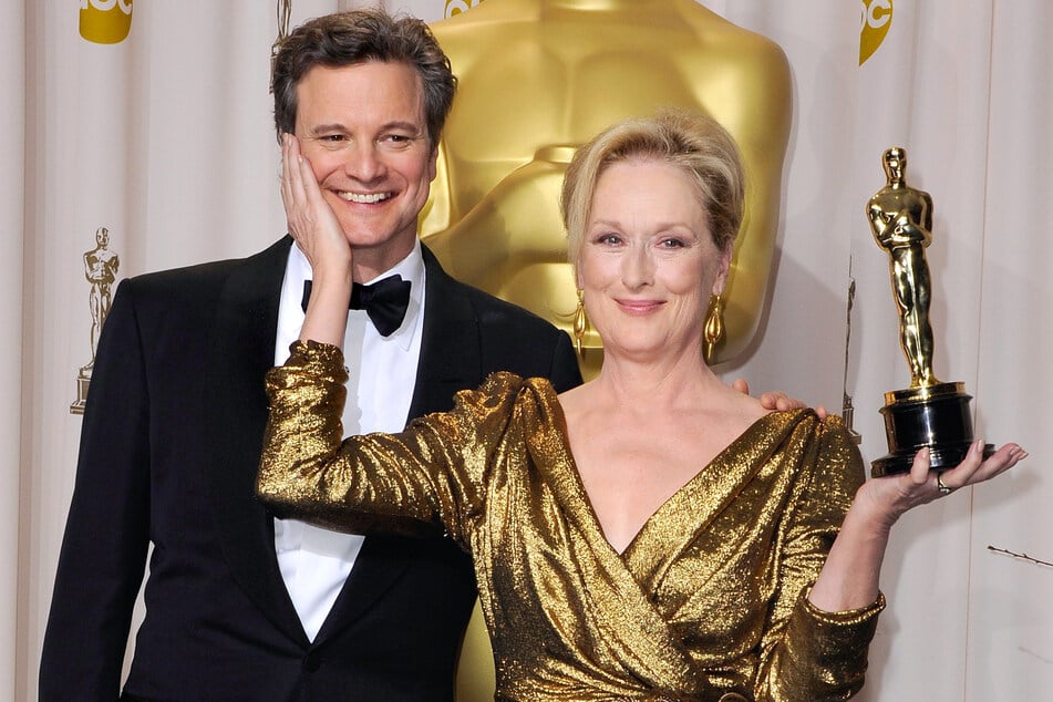 Meryl Streep holding the Oscar for her role in The Iron Lady, alongside Colin Firth during the 84th Academy Awards ceremony.