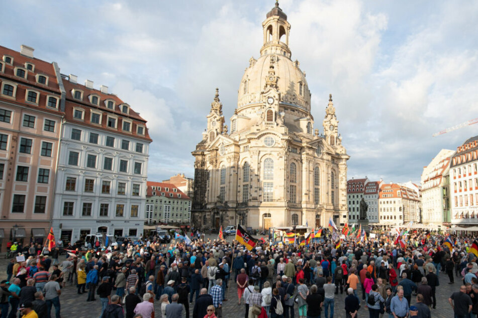 Teilnehmer stehen während einer Kundgebung der islam- und ausländerfeindlichen Pegida-Bewegung Ende August mit Fahnen auf dem Neumarkt. Den vorgeschriebenen Abstand sucht man hier vergebens. (Archivbild)