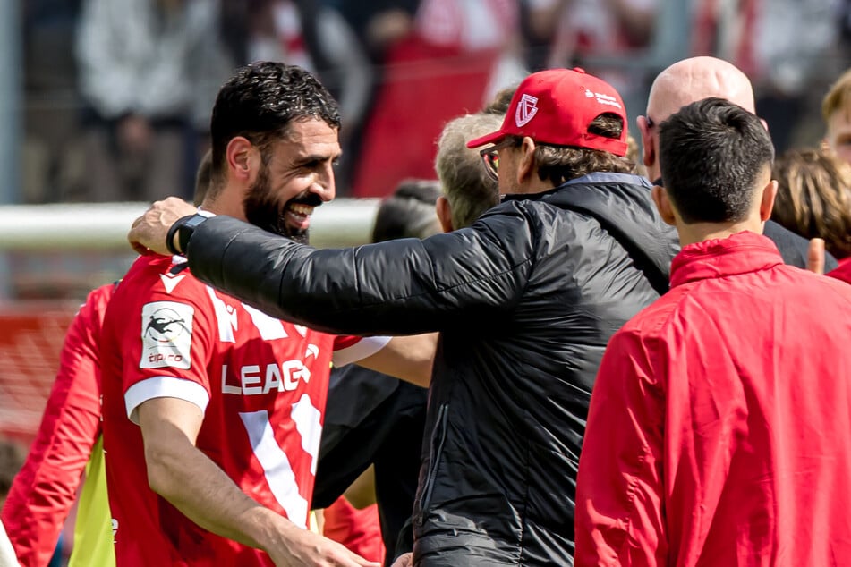 Trainer Pele Wollitz (M.) herzt Matchwinner Tolga Cigerci (l.)-