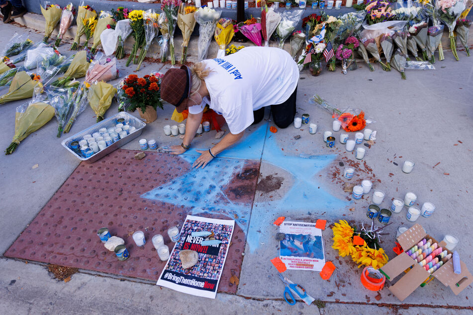 Elena Colombo of the Hamakom Synagogue draws a blue star in chalk around blood at the exact location on the sidewalk of the alleged assault on Paul Kessler in Thousand Oaks, California.