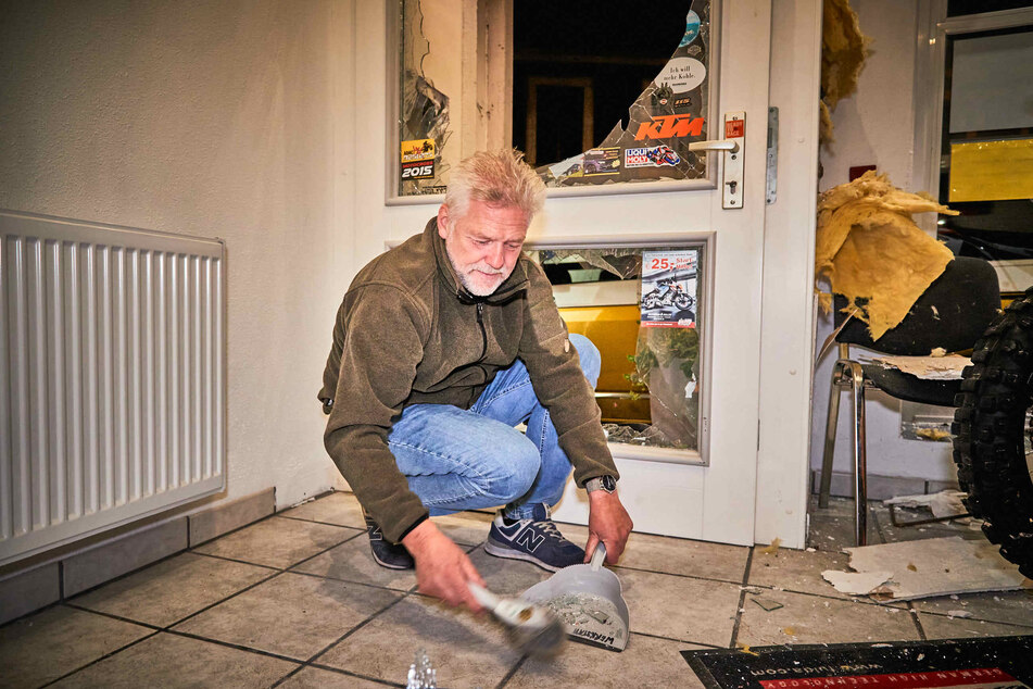 Der Innhaber der Fahrschule kehrt seinen Eingangsbereich mit Schaufel und Besen. Wer macht so etwas?