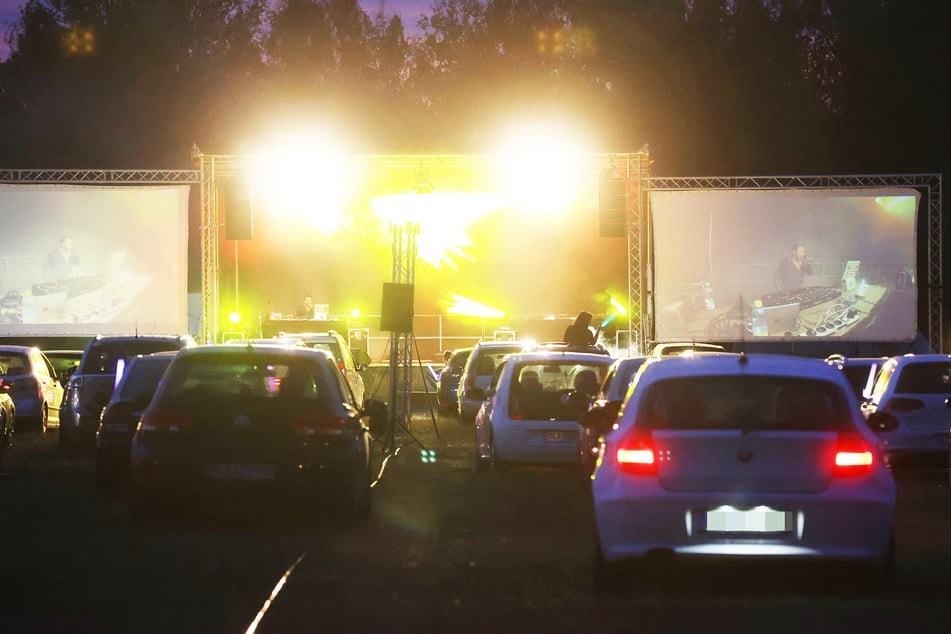 Besucher einer Autodisco im thüringischen Nobitz sitzen in ihren Fahrzeugen auf einer Wiese. (Symbolbild)