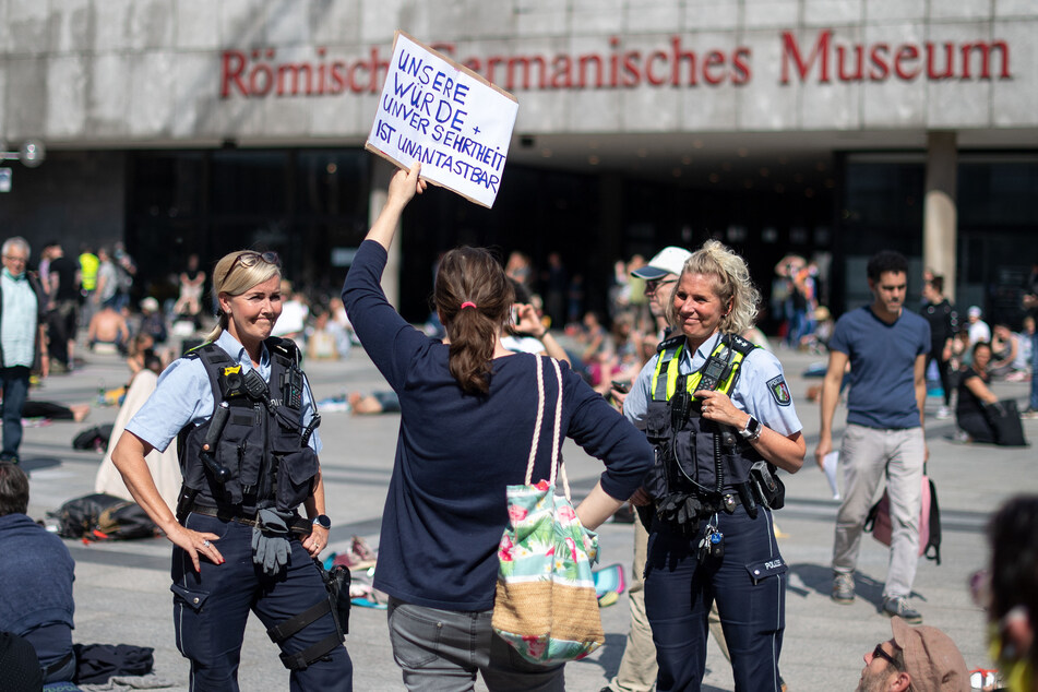Vergangene Woche in Köln: Polizisten diskutieren mit einer Frau, die an einer Versammlung gegen die Corona-Schutzmaßnahmen auf dem Roncalliplatz teilnimmt.