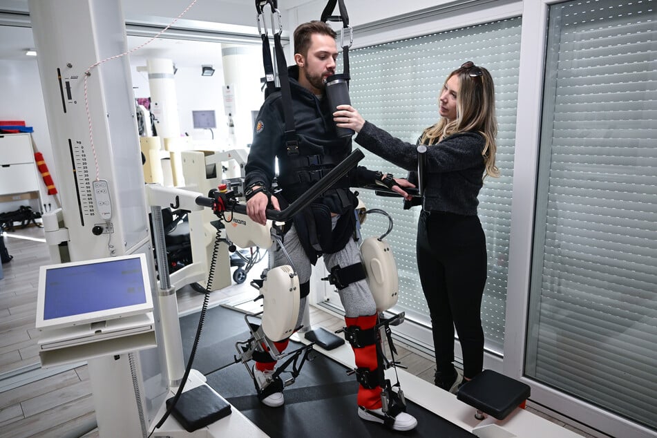 Mike Glemser (27) absolviert in einer Reha eine Übungseinheit bei einer Robotergestützten Gangtherapie. Rechts seine Freundin und Stütze Lara Lindmayer.