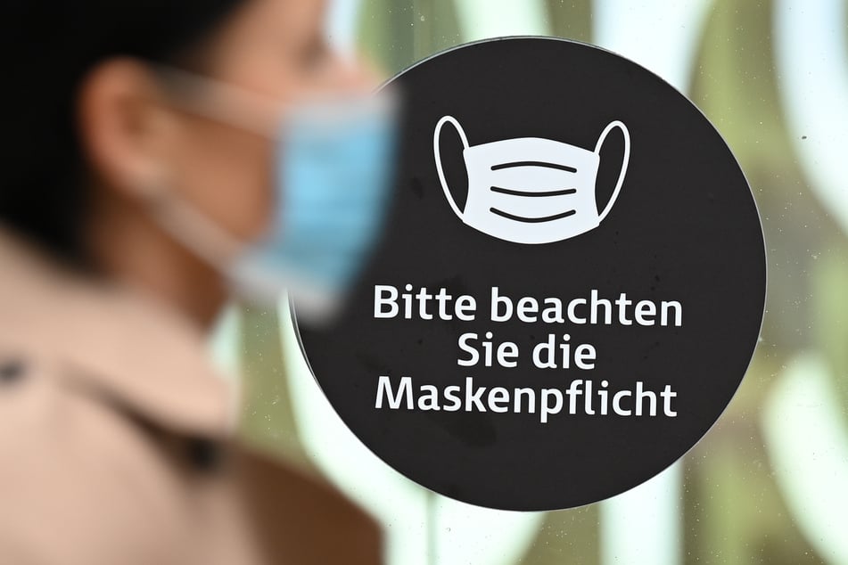 Eine Frau, die einen Mund-Nasen-Schutz trägt, geht auf der Frankfurter Einkaufsmeile Zeil an einem Aufkleber an einer Schaufensterscheibe mit der Aufschrift "Bitte beachten Sie die Maskenpflicht" vorbei.