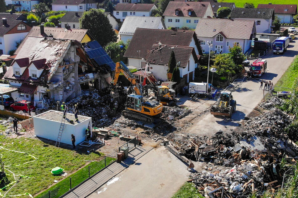 Zwei Bagger und ein Radlader sind bei Bergungsarbeiten an den Überresten eines Hauses im Einsatz, das am Donnerstag durch eine Explosion vollständig zerstört wurde.