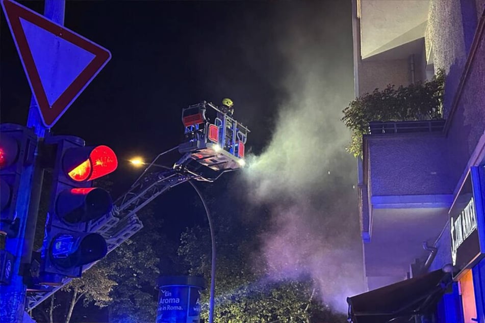 Die Wohnungen über dem brennenden Geschäft in der Greifswalder Straße werden von den Einsatzkräften über eine Drehleiter begutachtet.
