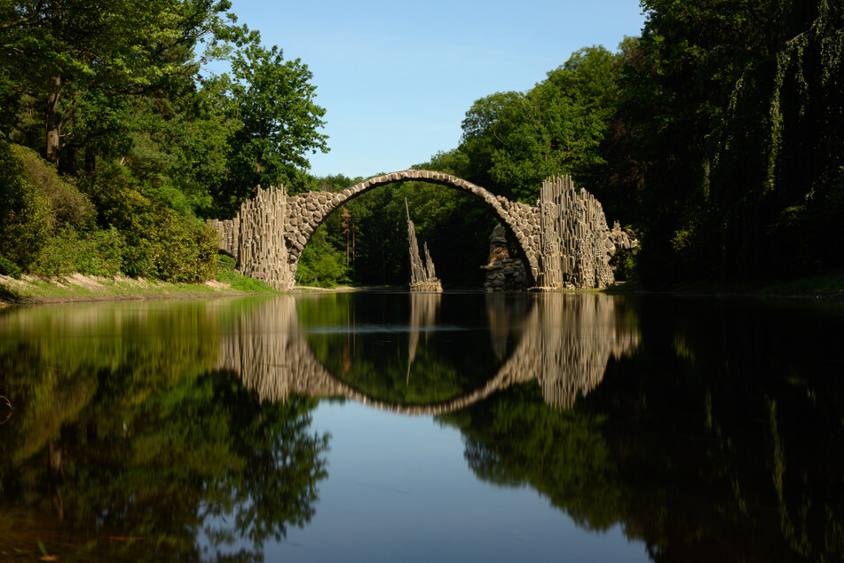 Umgeben von Azaleen und Rhododendren, bildet die Rakotzbrücke im Landkreis Görlitz einen steinernen Kreis im Wasser.