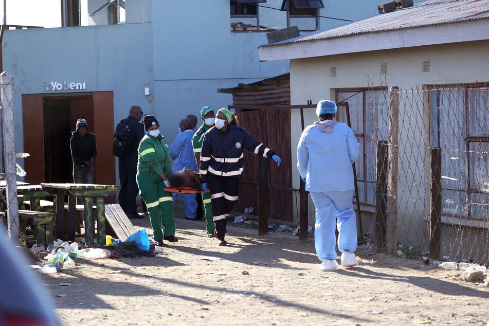 Einsatzkräfte tragen eine Leiche aus dem betroffenen Nachtclub in der südafrikanischen Stadt East London. Augenzeugen vermuteten eine Vergiftung der Besucher der Kneipe.
