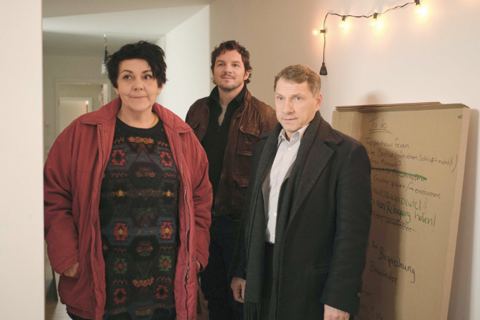 Ulrike (Christiane Rösinger) bringt die Kommissare Sebastian Bootz (Felix Klare) und Thorsten Lannert (Richy Müller, r) in den Gemeinschaftsraum des Hauses in einer Szene des "Tatort: Das ist unser Haus" (undatierte Filmszene).