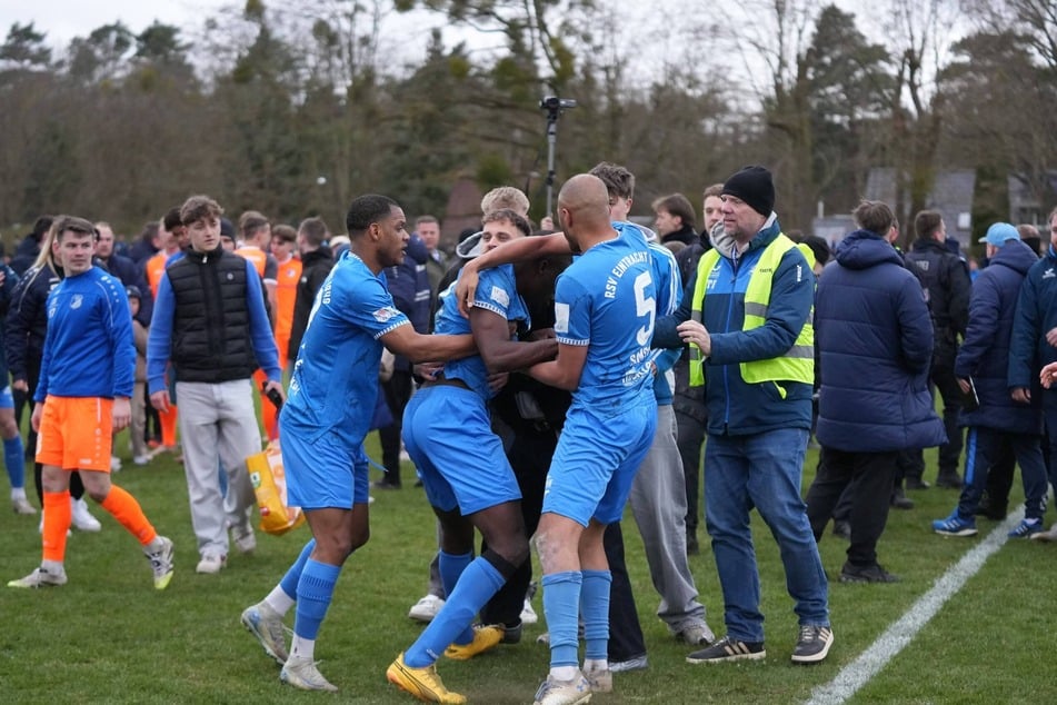 Der aufgebrachte Saheed Mustapha (31, M.) muss von seinen Teamkollegen zurückgehalten werden.