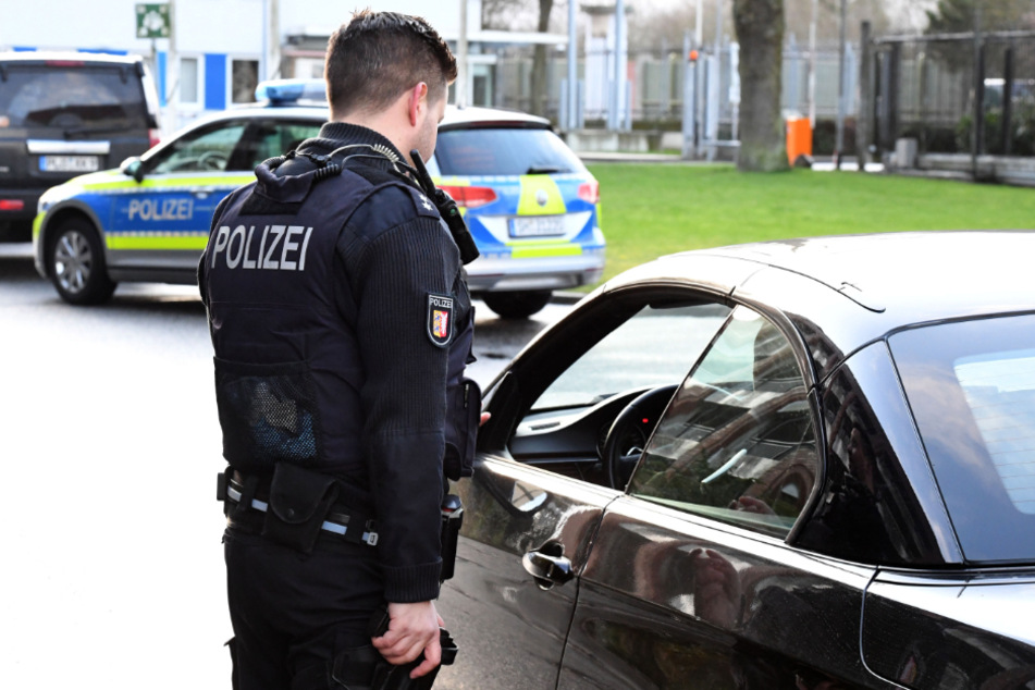 Ein Polizist kontrolliert einen Autofahrer. (Symbolbild)