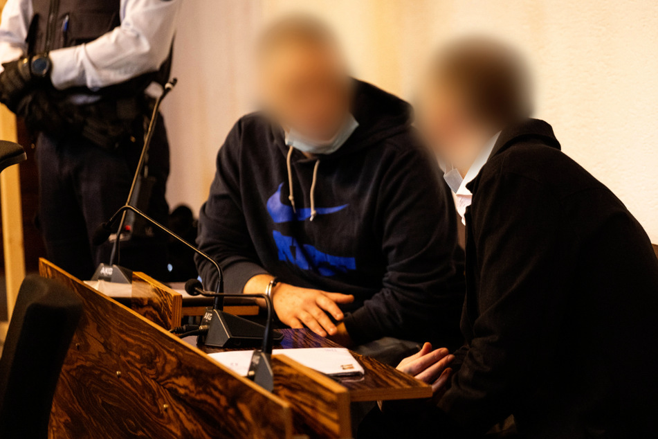 Die zwei Angeklagten sitzen im Landgericht in Freiburg und unterhalten sich.