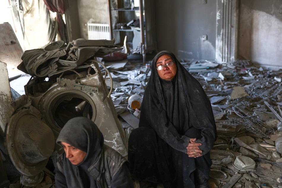 Women sit at a home damaged by a strike in Tehran, Iran, on March 30, 2026.