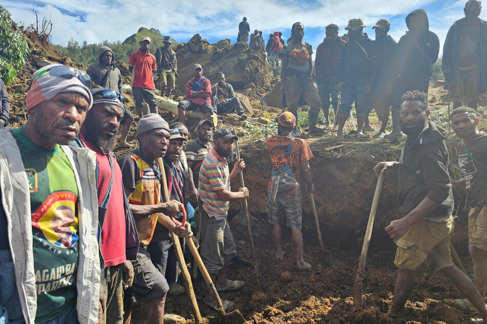 Locals gather amid the damage after a landslide in Maip Mulitaka, Enga province, Papua New Guinea.