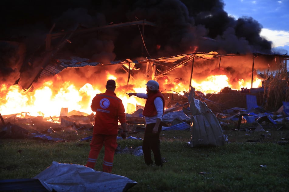 Mitarbeiter des Zivilschutzes kontrollieren ein brennendes und zerstörtes Lagerhaus in einem Industriegebiet, das bei israelischen Angriffen getroffen wurde.
