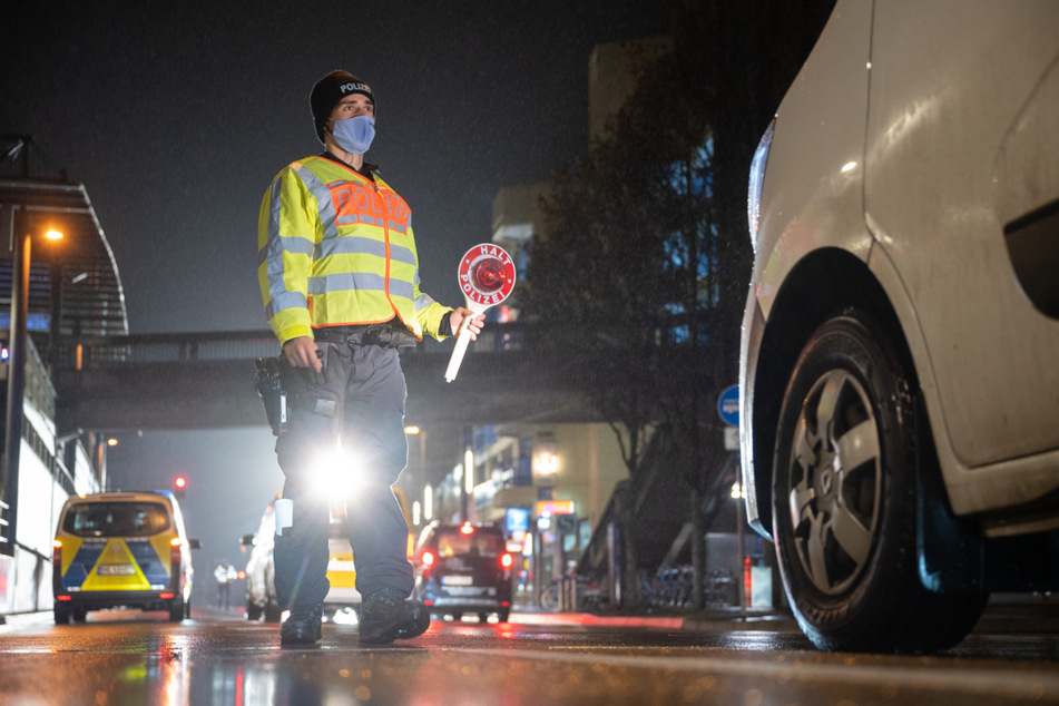 Stuttgart: Ein Polizist winkt während einer Kontrolle zur Einhaltung der Ausgangsbeschränkungen ein Auto raus.