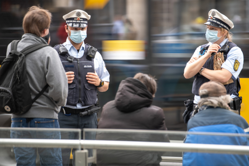 Polizeibeamte sprechen an einer Haltestelle in Stuttgart drei Männer an.