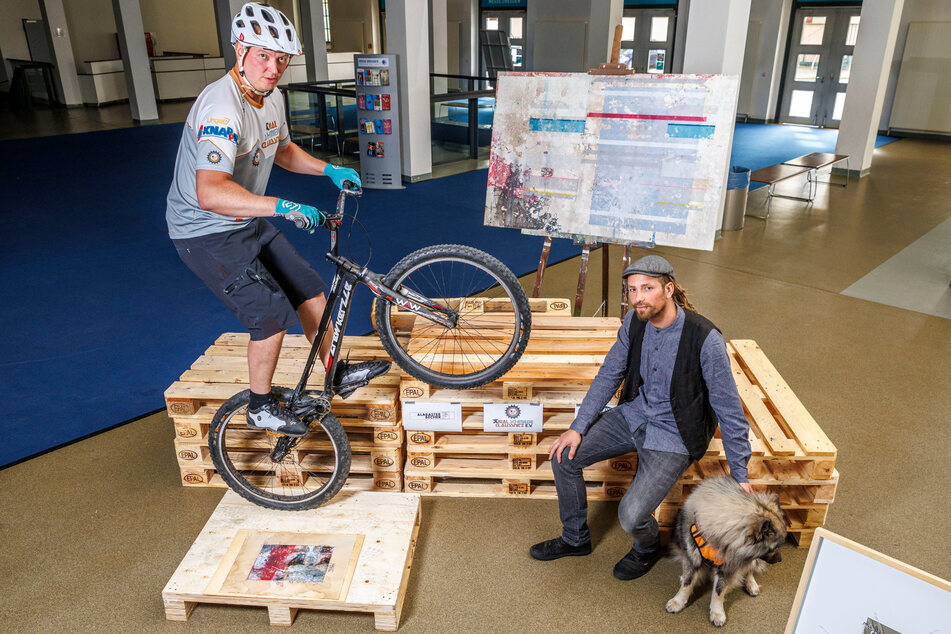 Künstler Alabaster Becher (33) erklärt das "Reis-Leim-Verfahren": Dabei springt Trial-Bike-Fahrer Ralf Hesse (41) auf die Druckplatte, presst so Farbe aufs Papier.