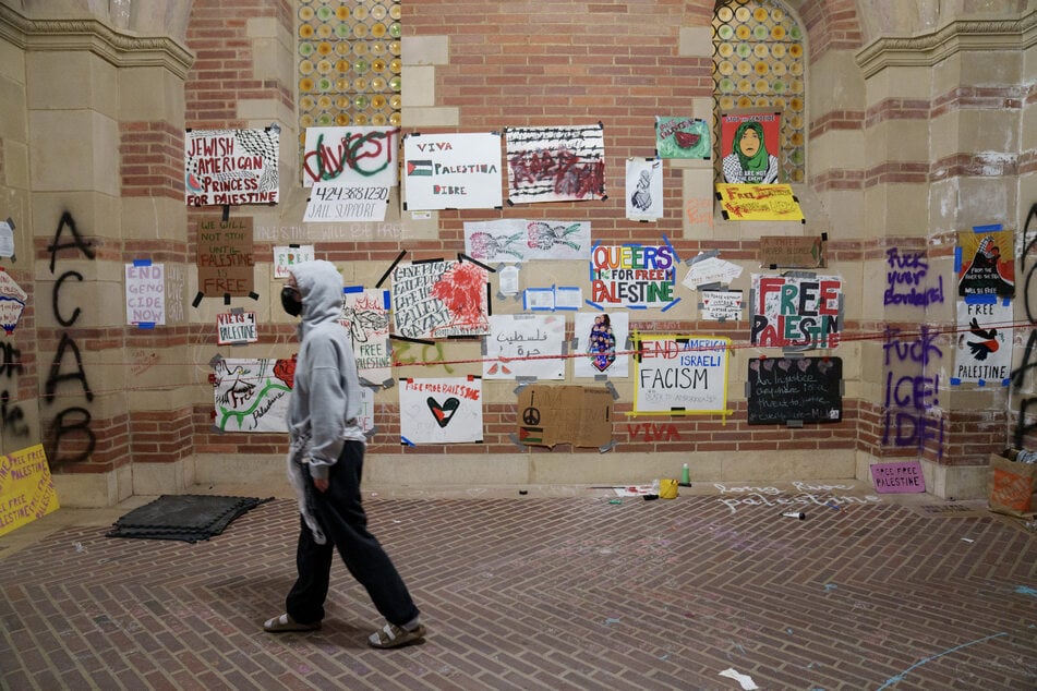 A protester walks by signs at a Palestine solidarity encampment on the UCLA campus on May 2, 2024.